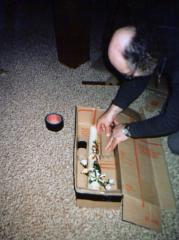 Frits Spies pakt kaars met symbool en witte bloemen in verzenddoos