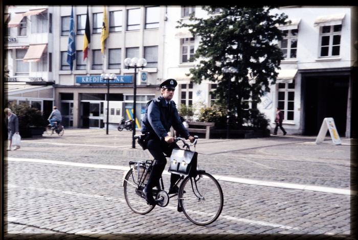 Wijkagent Cis Oris op zijn fiets langs de westzijde op de Grote Markt te Turnhout.