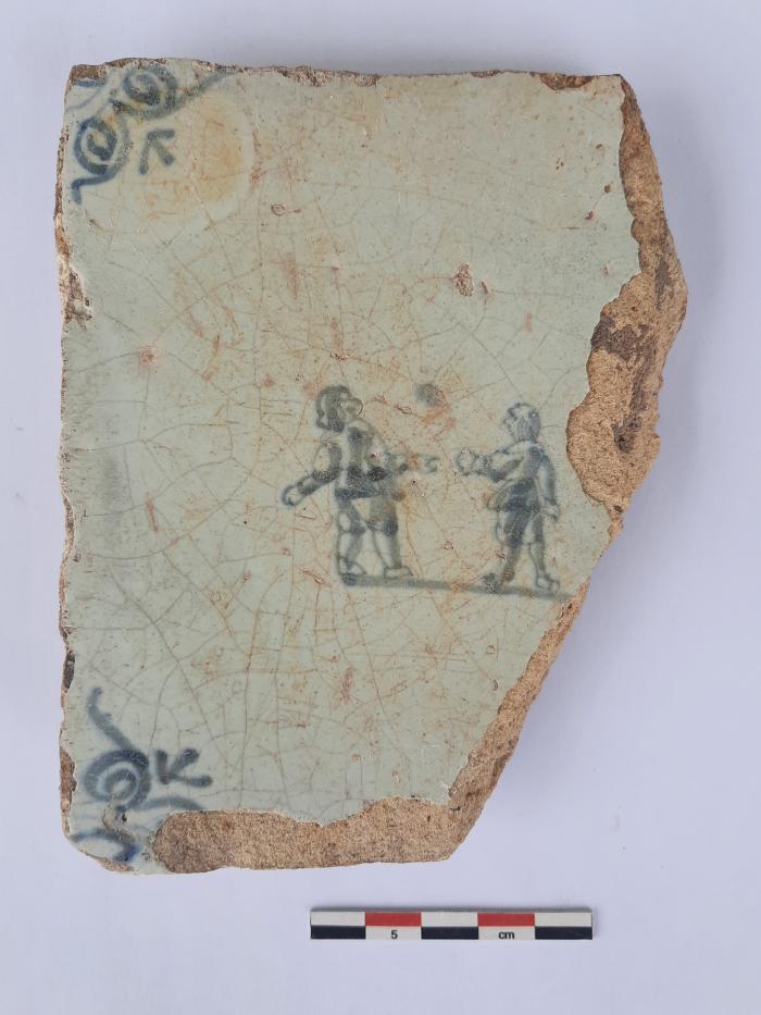 Tegel met twee kaatsende figuren, ossekop als hoekmotief.