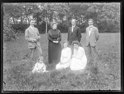 Familiefoto van drie vrouwen, drie mannen en een klein meisje
