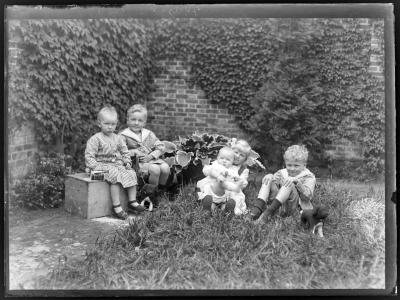 Vier kinderen met baby in de hoek van de tuin