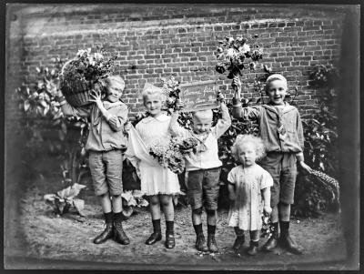 Vijf kinderen met bloemen en een bord dat vermeldt: "Bonne fête! Cher Bon-Papa"