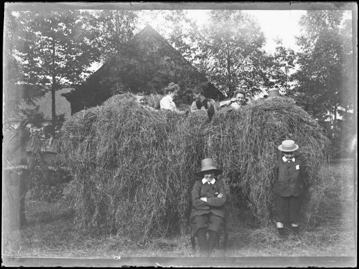Zes mensen voor en op een hooiwagen
