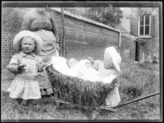 Vrouw met twee peuters en een baby gelegen in een miniatuur hooiwagen
