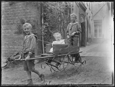 Een jongen en een peuter in een speelgoedkar getrokken door een derde