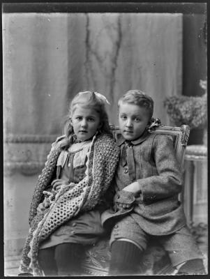 Meisje met grote sjaal en een jongen op een stoel